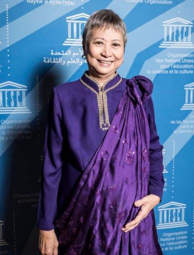 Mrs. Cecile Alvarez, UNESCO Artist for Peace and SSCC Policy Advisory Board Member, is seen wearing a traditional purple outfit, standing in front of a UNESCO-branded backdrop