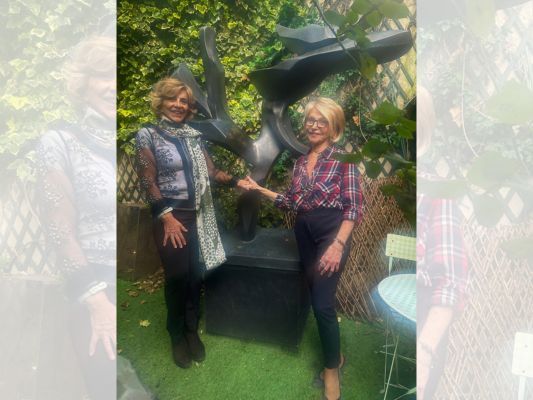 Claudia Turbay, Director of External Affairs at SSCC, and Hedva Ser, UNESCO Goodwill Ambassador for Cultural Diplomacy, standing outdoors with the large metal Tree of Peace sculpture visible behind them. The abstract branched sculpture represents UNESCO's symbol for the culture of peace initiatives. Turbay and Ser are posing in front of the impressive artwork.