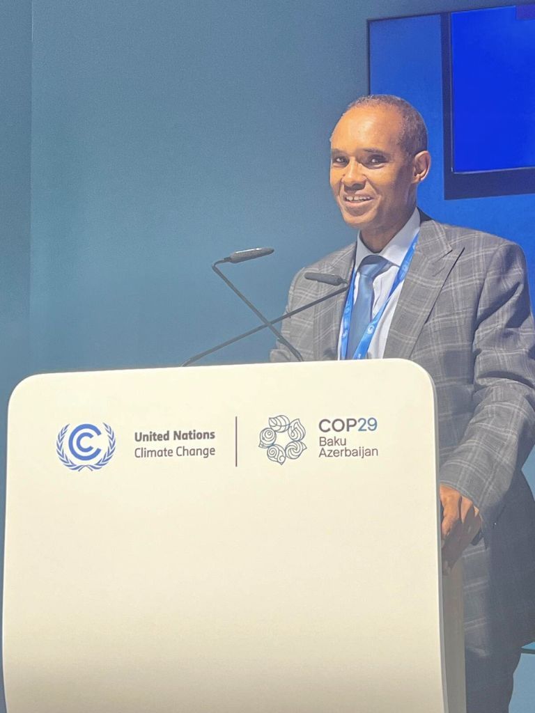 Ali Mohamed, Special Envoy on Climate Change to the President of Kenya, delivering a speech at a COP29 side event. He stands behind a podium displaying the United Nations Climate Change and COP29 Baku Azerbaijan logos, addressing climate-related topics.