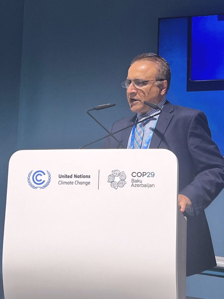 Nasir Khattak, Vice President and Chief Operating Officer of the Climate Institute, delivering a speech at a COP29 side event. He is standing behind a podium displaying the United Nations Climate Change and COP29 Baku Azerbaijan logos, discussing climate strategies and solutions.